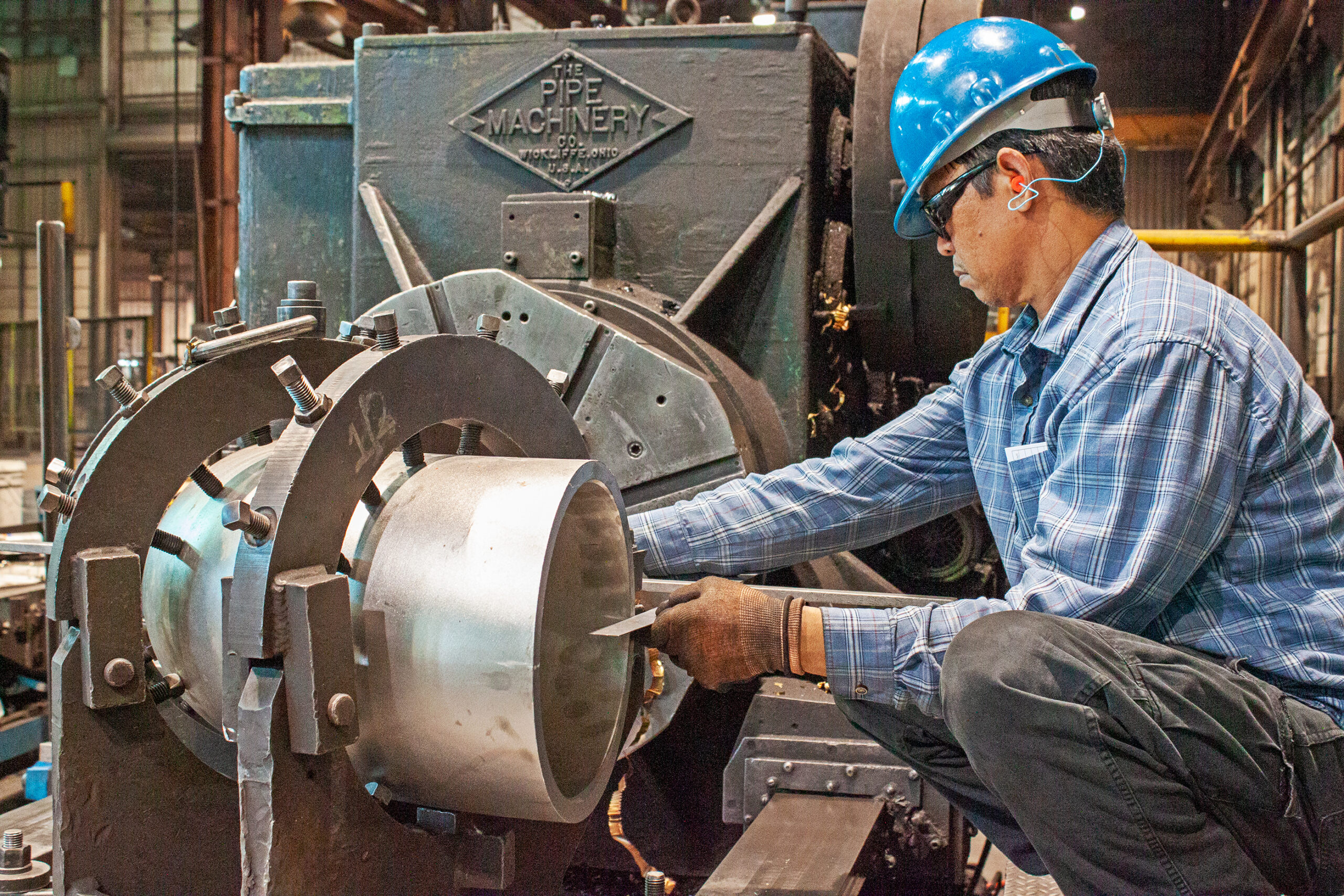 Engineer wearing a hard hat measuring the inner wall dimensions of a steel fitting.